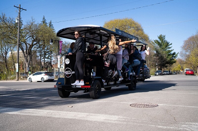 Large group on their pedal pub crawl ride caught while driving the pedal tavern